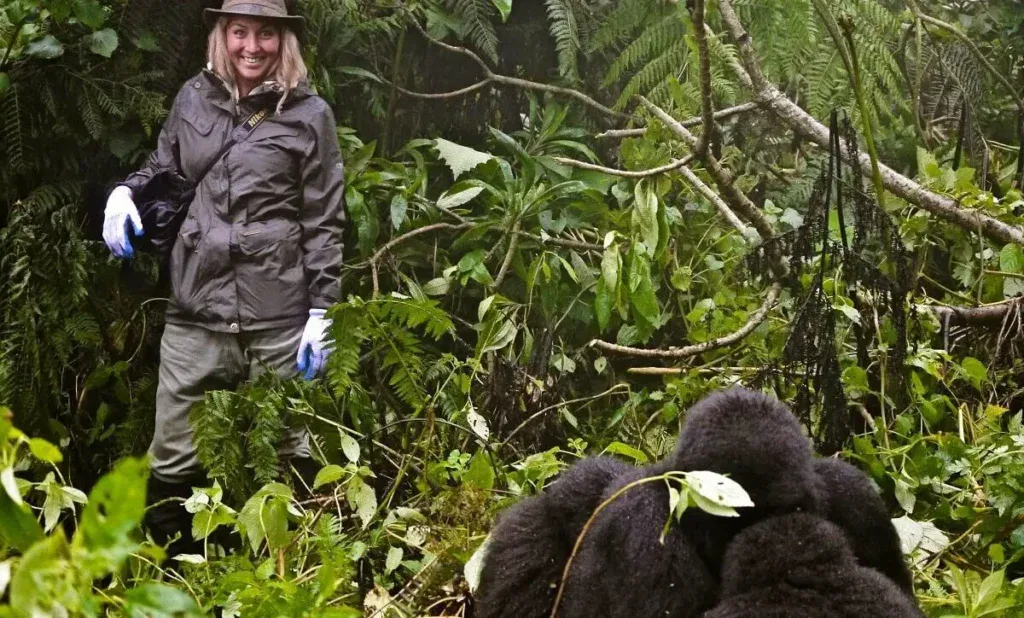 Tourists wearing proper clothing for gorilla trekking in Uganda, including hiking boots, long trousers, and rain jackets while walking through a rainforest.