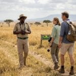 Safari guide and travelers in Ugandan savanna