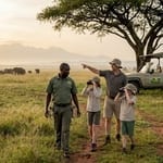 Family with guide walking on safari trail in Uganda