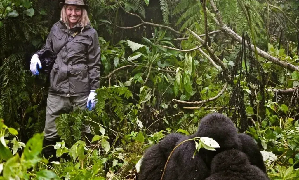 Tourists wearing proper clothing for gorilla trekking in Uganda, including hiking boots, long trousers, and rain jackets while walking through a rainforest.